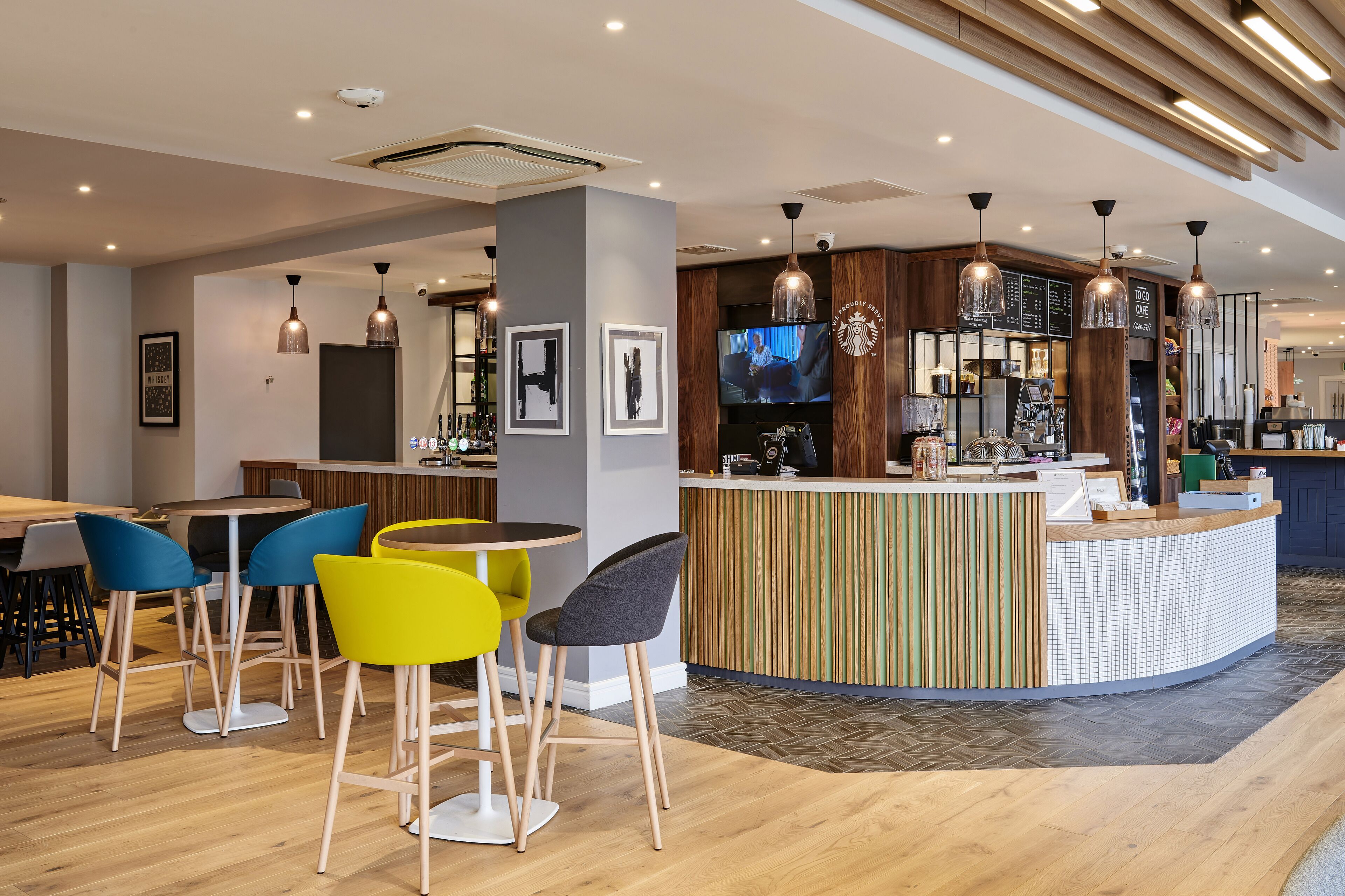 A modern bar area with a counter, bar stools, and a television screen.