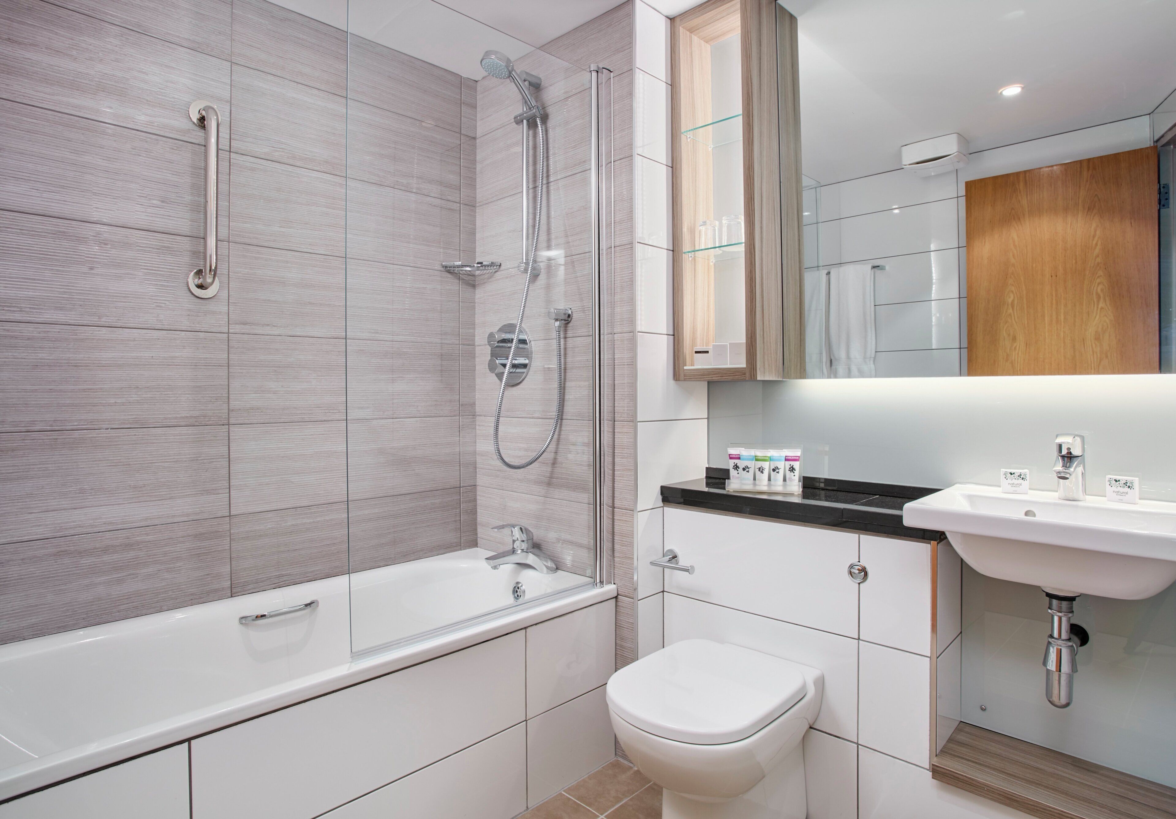 A modern bathroom with a bathtub, shower, toilet, and sink.
