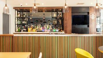 A bar area with a wooden slat wall, multiple liquor bottles, and a television screen.