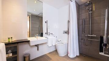Ein modernes Badezimmer mit Waschbecken, Toilette, Dusche und einem großen Spiegel.