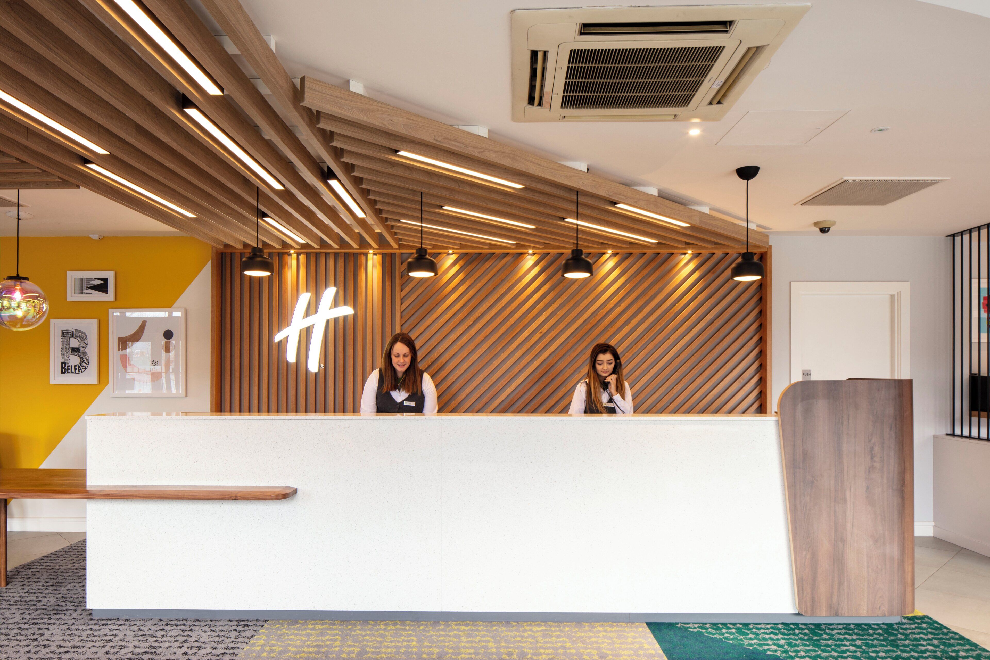 A reception desk with a modern design, featuring a wooden slat wall and pendant lighting.