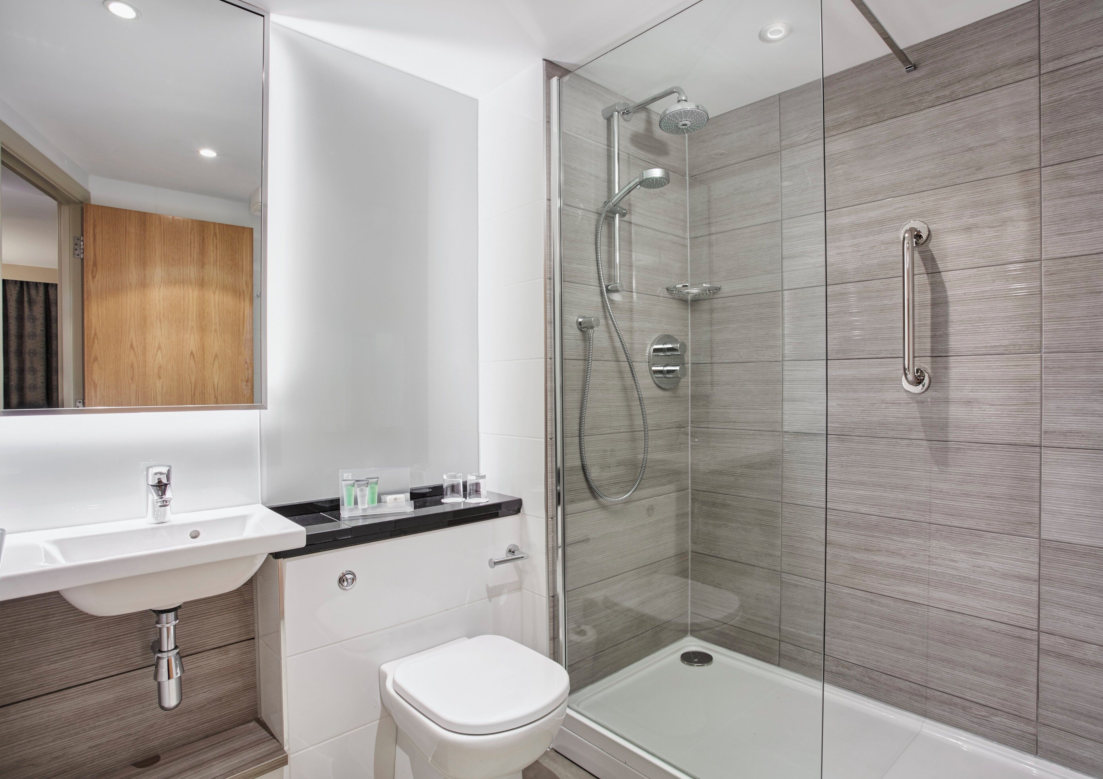 A modern bathroom with a glass-enclosed shower, a white sink, and a toilet.