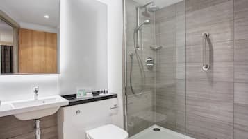A modern bathroom with a glass-enclosed shower, a white sink, and a toilet.