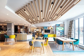 A modern interior with a bar area, seating, and a large window. - Holiday Inn Belfast City Centre by IHG (Belfast)