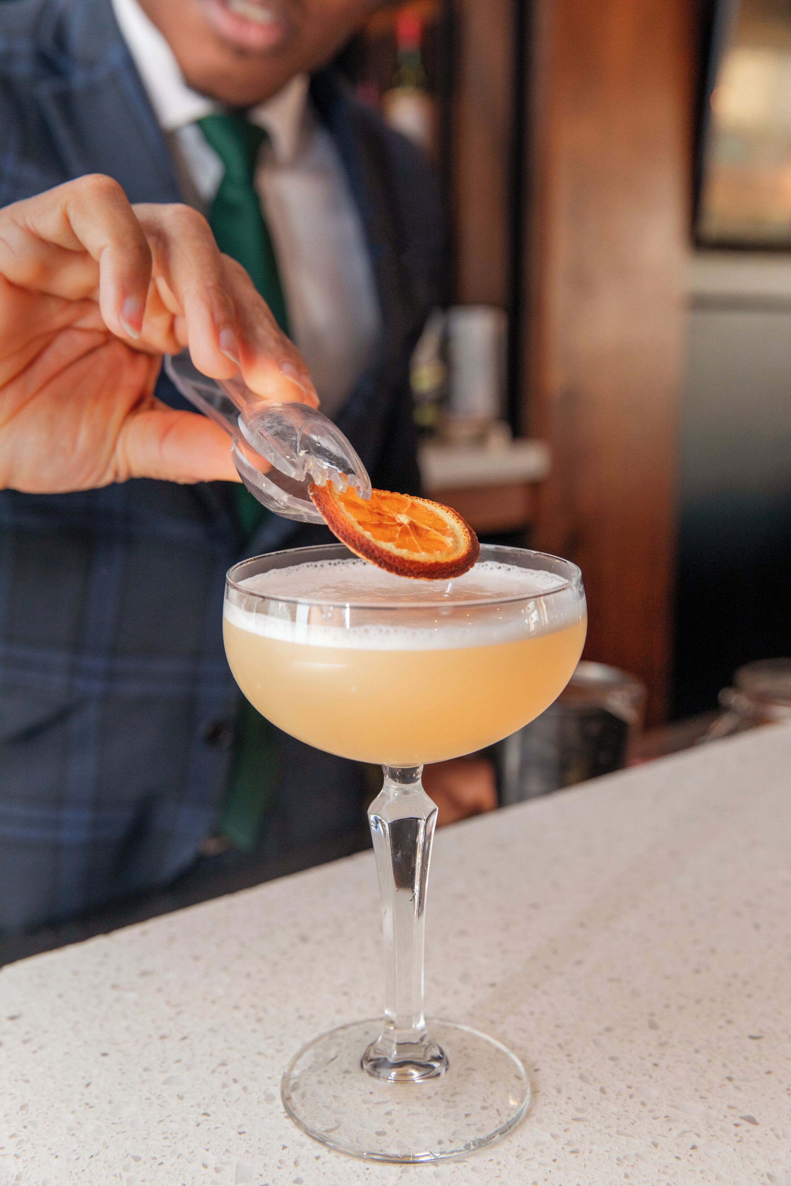 A cocktail in a stemmed glass with a slice of orange garnish.