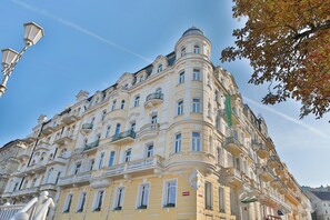 A historic building with multiple balconies, ornate architectural details, and a clear blue sky. - Belvedere Spa & Wellness (Marianske Lazne)