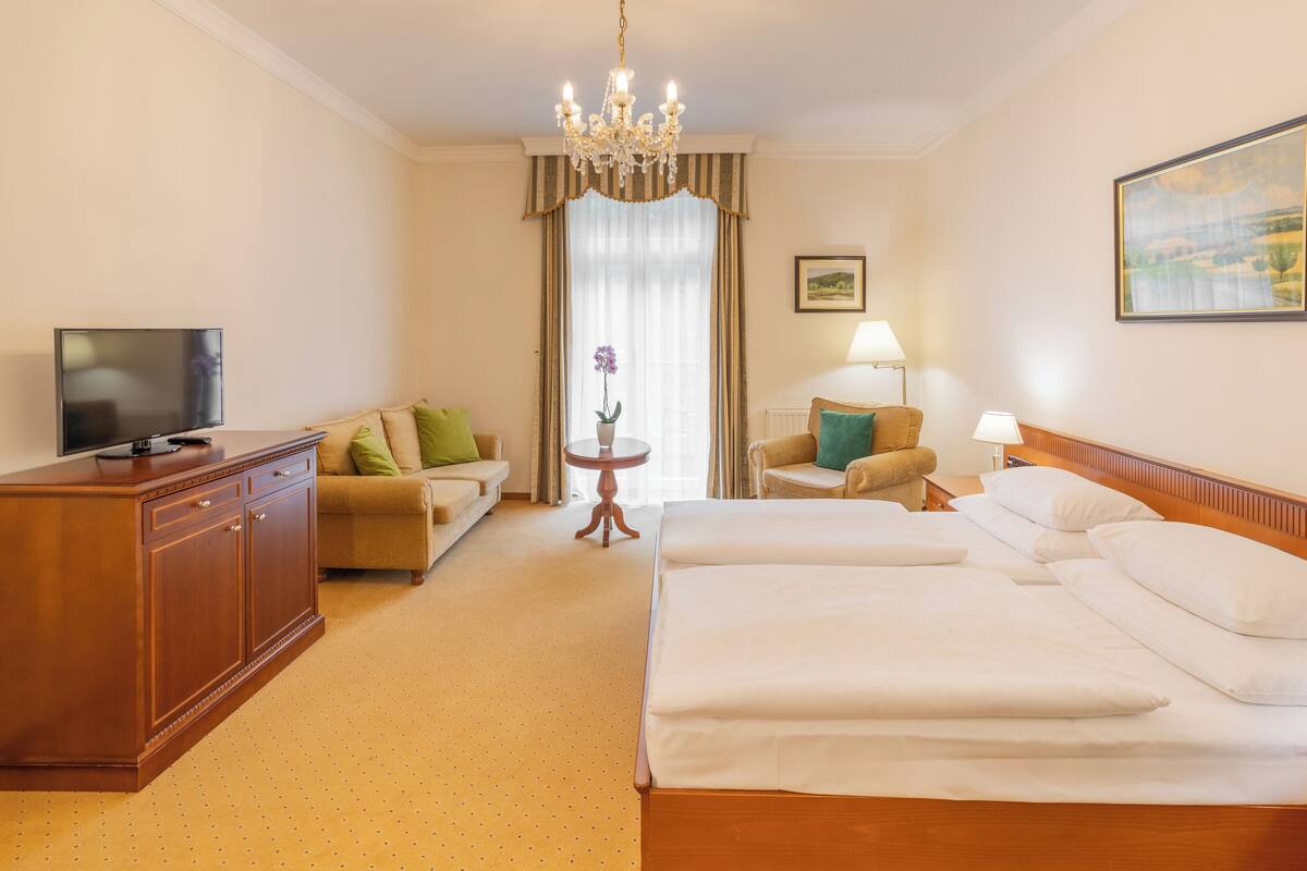 Een hotelkamer met een groot bed, een bureau, een televisie, een lamp en een schilderij aan de muur.