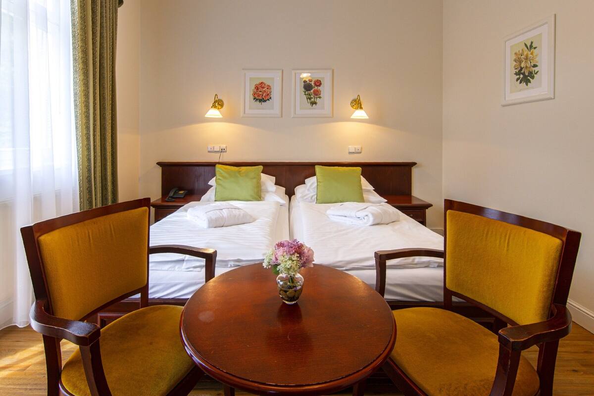 Een hotelkamer met een bed, twee stoelen, een tafel en een kroonluchter.