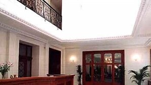 A lobby with a reception desk, a large wooden door, and a patterned floor. - Parkhotel Richmond (Karlovy Vary)