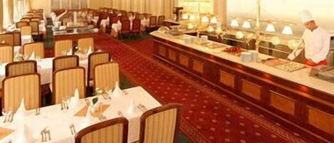 Un comedor formal con varias mesas, sillas y una larga barra tipo buffet.