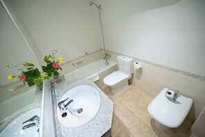 A bathroom with a sink, toilet, bidet, and shower.