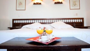 A neatly made bed with a wooden headboard, a bedside table with a tray of orange juice and a cup, and wall-mounted lamps. - Hospedium Hotel Juan II (Toro)