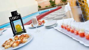 A table set with plates of appetizers, a candle, a glass pitcher, and a drink tray. - Hospedium Hotel Juan II (Toro)