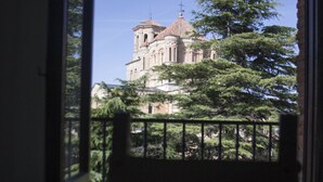 A view from a balcony with a railing, overlooking a large building with a dome and cross, surrounded by trees. - Hospedium Hotel Juan II (Toro)