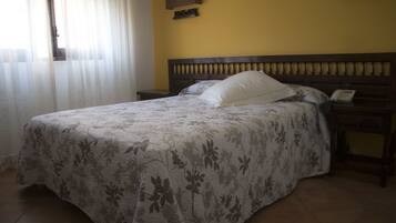 A bed with a floral bedspread, a nightstand with a phone, and a wall-mounted shelf.