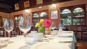 A restaurant with a wooden interior, a bar with wine bottles, and a table set for dining. - Hospedium Hotel Juan II (Toro)