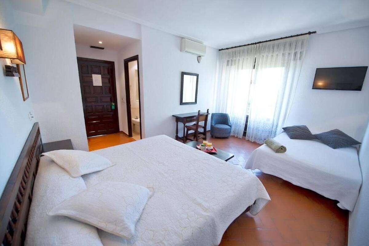 A hotel room with two beds, a desk, a chair, and a TV.