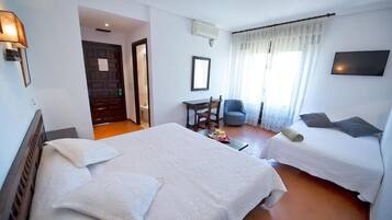 A hotel room with two beds, a desk, a chair, and a TV.