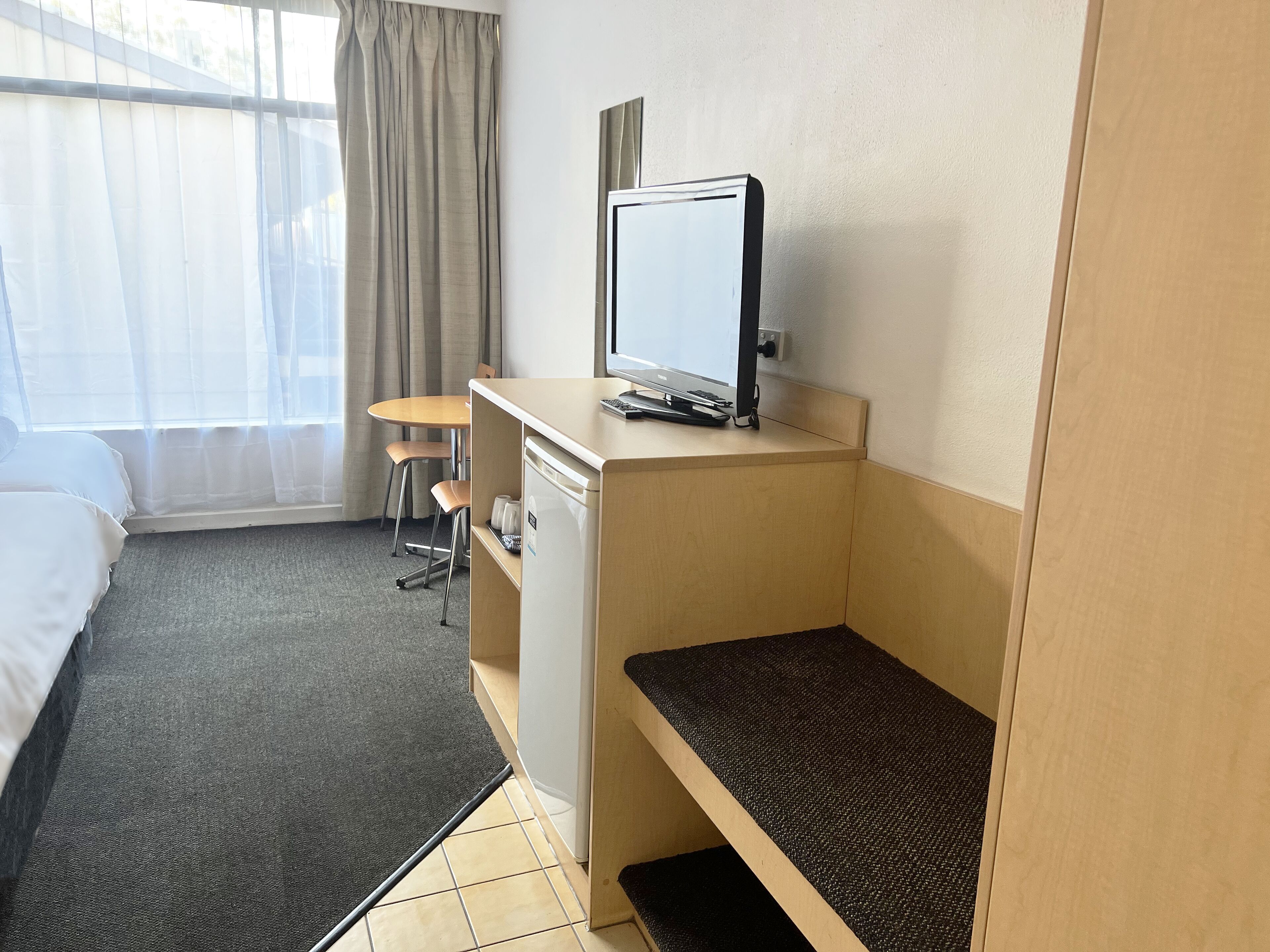 Une chambre d’hôtel avec un lit, un bureau avec un ordinateur, une chaise et une petite table.