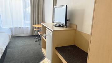 Une chambre d’hôtel avec un lit, un bureau avec un ordinateur, une chaise et une petite table.