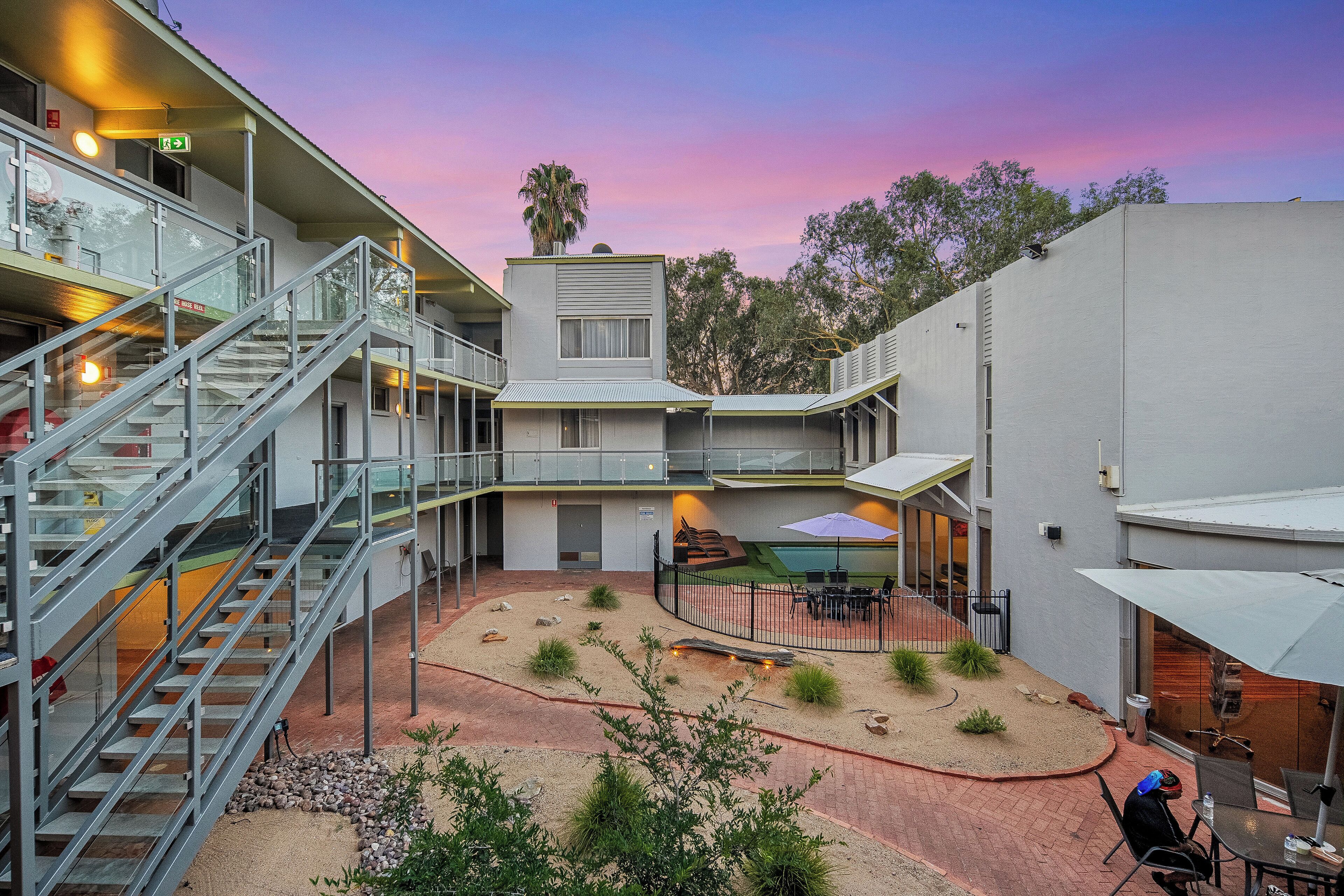 A modern building with multiple floors, outdoor seating, and a landscaped courtyard.