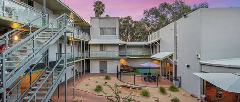A modern building with multiple floors, outdoor seating, and a landscaped courtyard.
