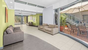 En rummelig lobby med en grå sofa, en beige sofa og et spiseområde med udendørs siddepladser.