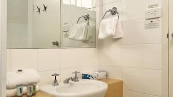 A bathroom with a white sink, mirror, and two towel racks. There are toiletries on the sink counter.