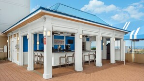 A small, white building with a blue roof and a bar area with stools.