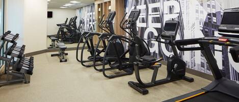 A gym with multiple treadmills, ellipticals, and weight machines.