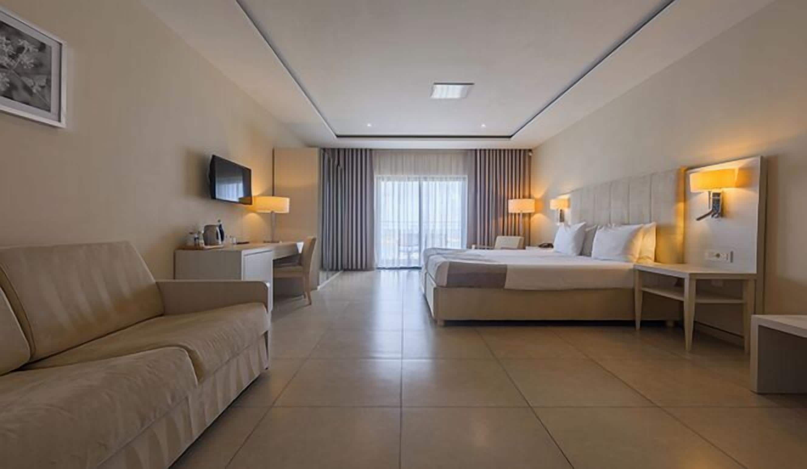 A hotel room with a bed, a sofa, a desk, and a TV.