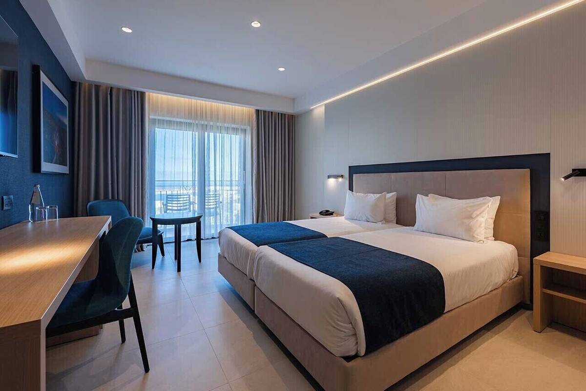 Una habitación de hotel moderna con una cama grande, un escritorio y una silla.