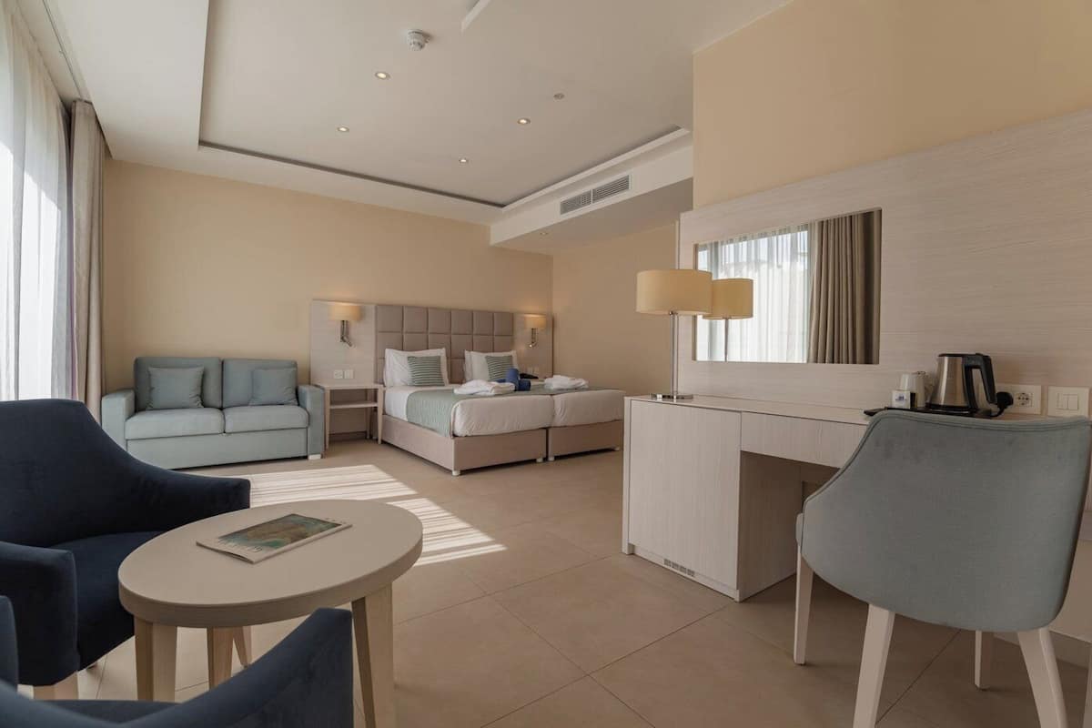 Habitación de hotel moderna con cama, sofá, escritorio y silla.