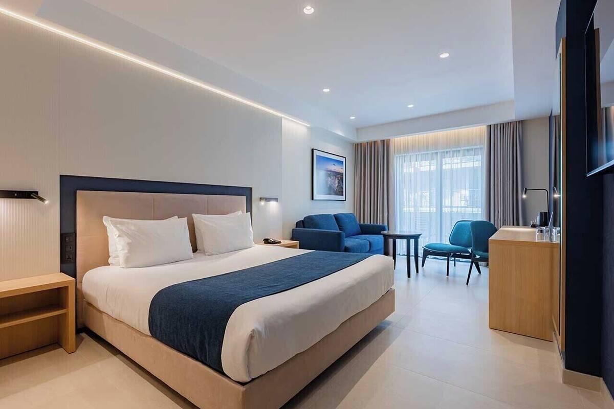 Una habitación de hotel moderna con una cama grande, un escritorio, una silla y un televisor.