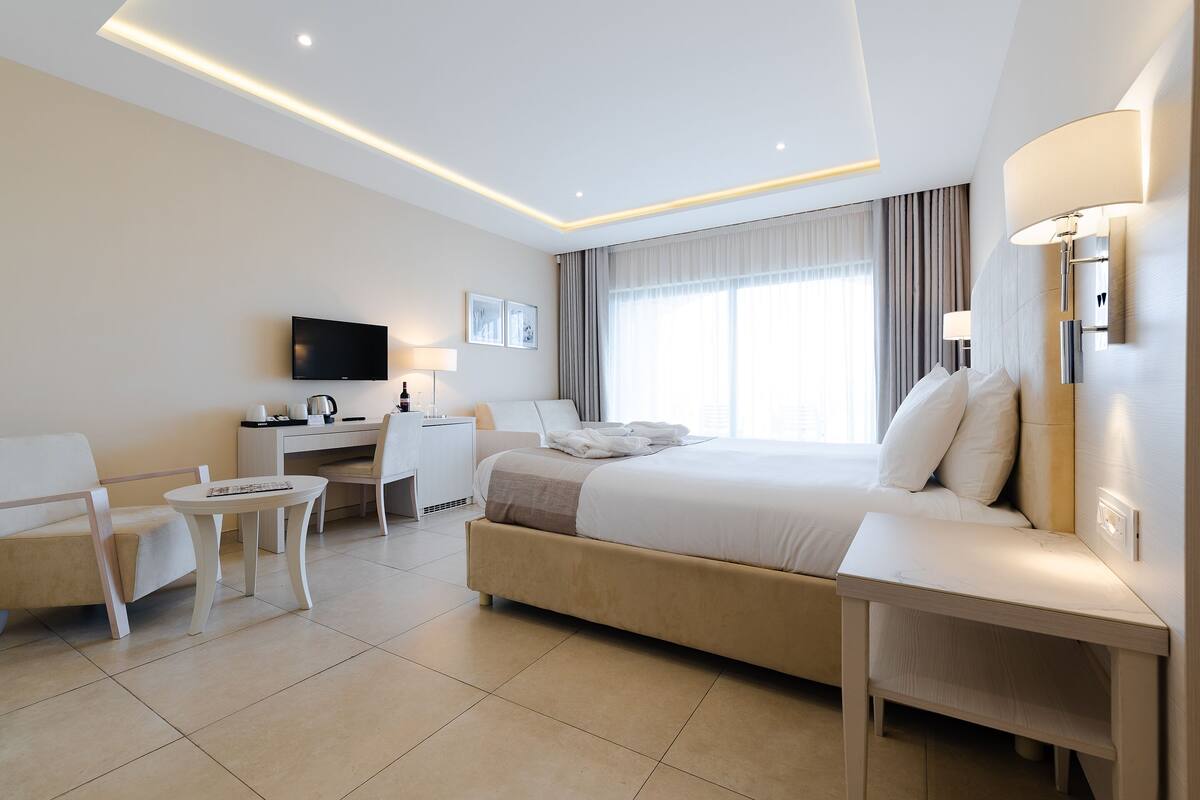 Una habitación de hotel moderna con una cama grande, un escritorio, una silla y un televisor.