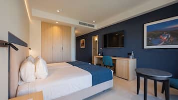 Habitación de hotel con dos camas, un escritorio, una silla, una mesita y un cuadro en la pared.