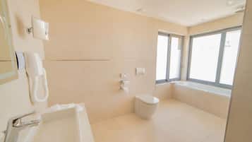 Un baño moderno con bañera, inodoro y un amplio ventanal que proporciona luz natural.