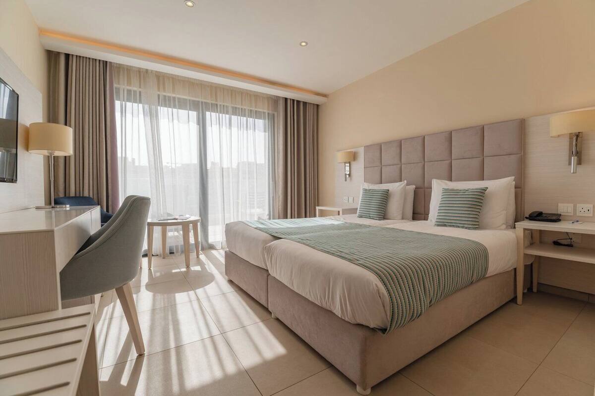 Habitación de hotel moderna con una cama grande, un escritorio, una silla y una pequeña mesa.
