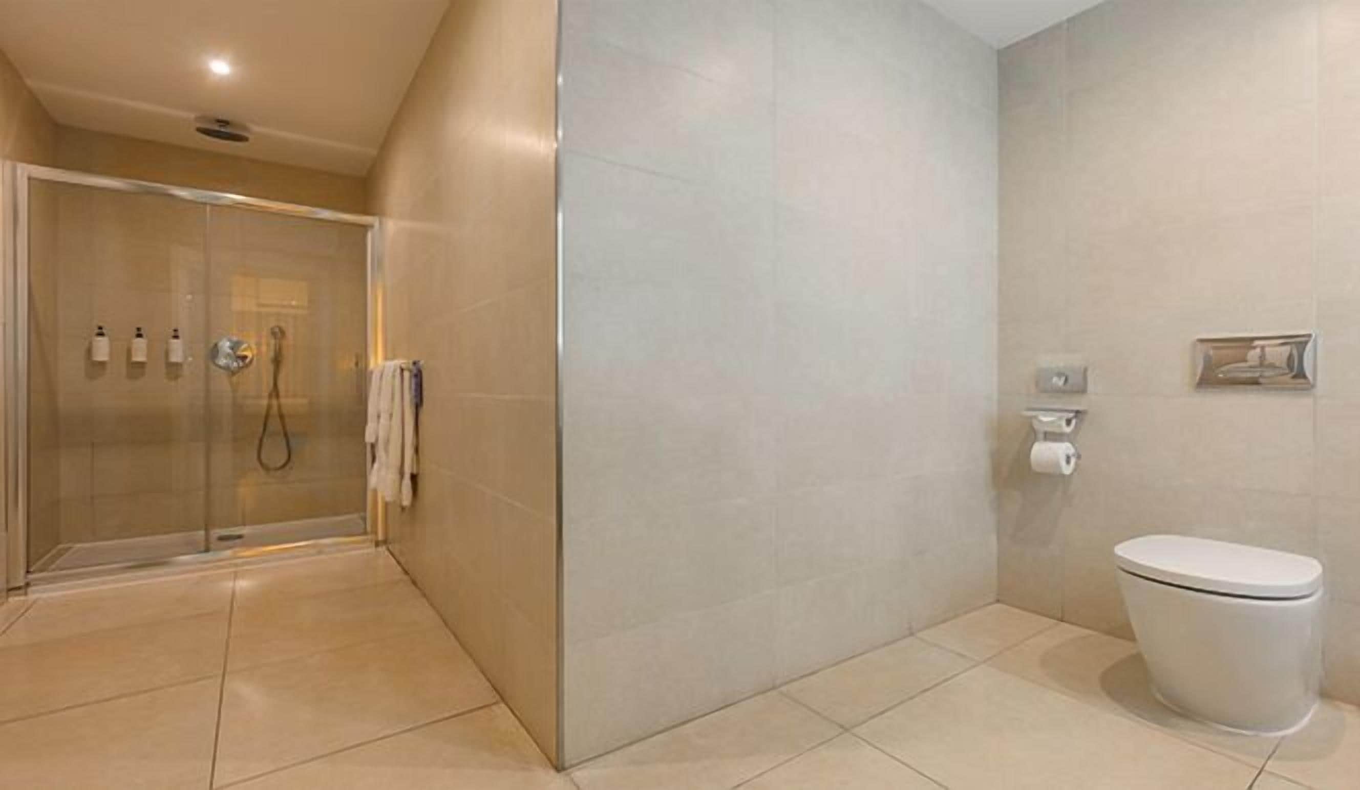 A modern bathroom with a glass-enclosed shower, a toilet, and a sink with a mirror.