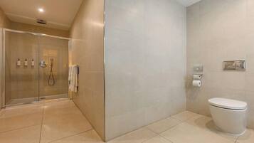 A modern bathroom with a glass-enclosed shower, a toilet, and a sink with a mirror.