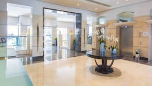 A modern lobby with a polished floor, a round table with vases, and a reception desk.