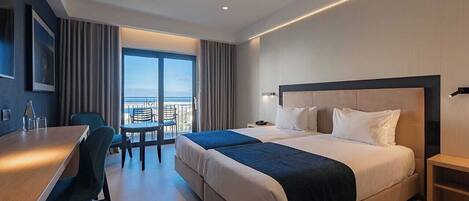 Una habitación de hotel moderna con una cama grande, un escritorio y un balcón con vistas.