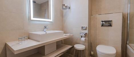 A modern bathroom with a large mirror, a sink, a toilet, and a shower area.