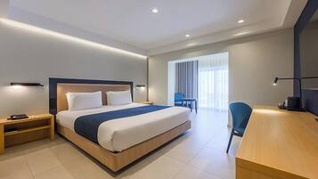 A modern hotel room with a large bed, bedside tables, a desk, and a chair.