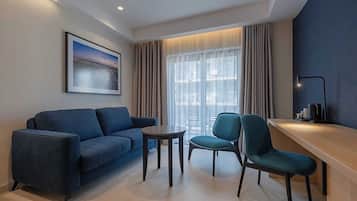 A modern living room with a blue sofa, two chairs, a small round table, and a large window with curtains.