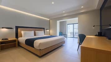 Una habitación de hotel moderna con una cama grande, mesitas de noche, un escritorio y vistas al balcón exterior.