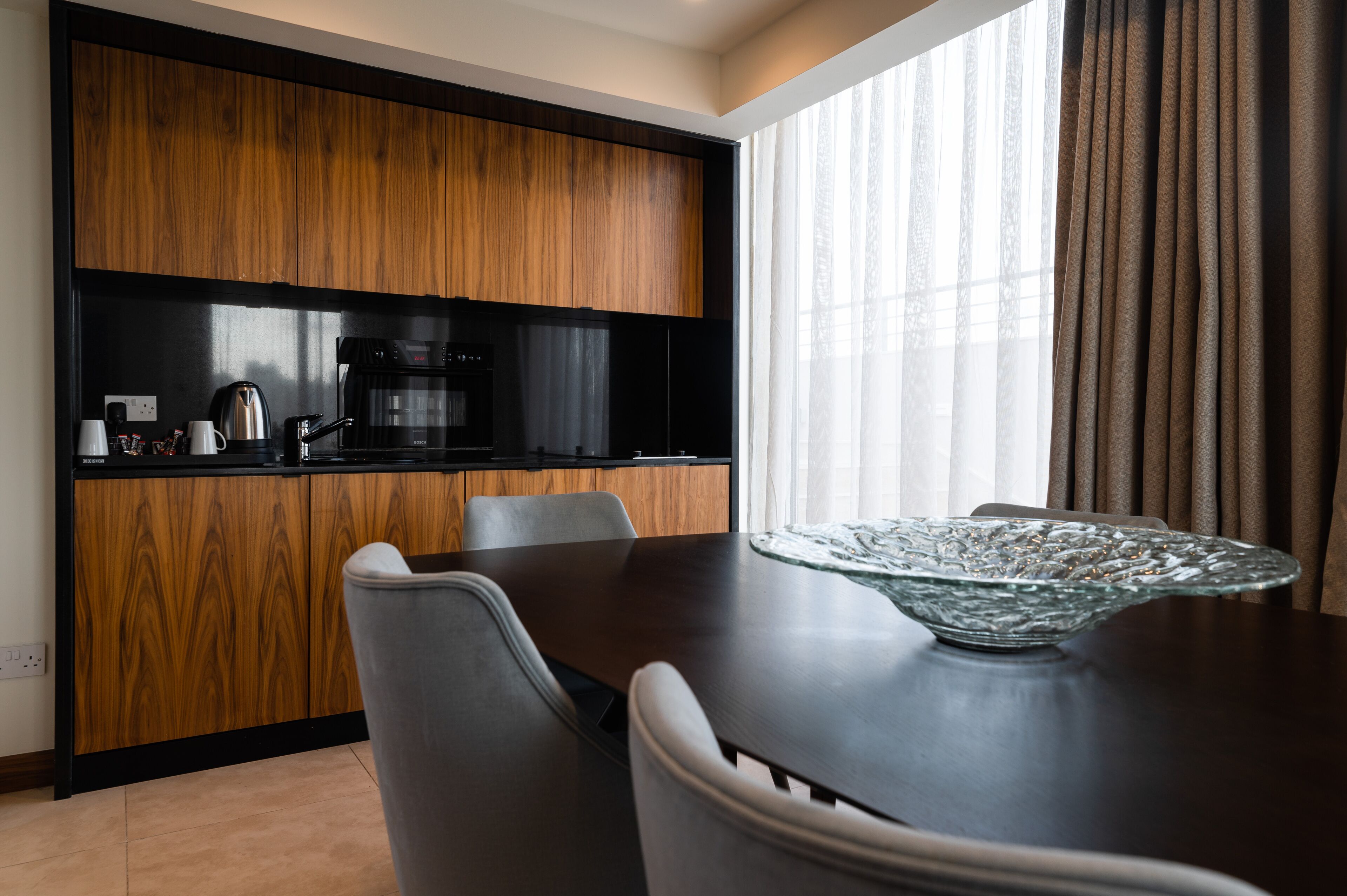Una cucina moderna con mobili in legno e un'area pranzo con un tavolo centrale in vetro.