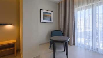 A modern hotel room with a large window, a round table, a chair, and a framed picture on the wall.