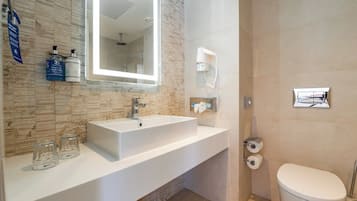 A modern bathroom with a large sink, a mirror, a shower, and a toilet.