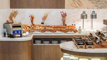 A buffet setup with various food items, a coffee machine, and a decorative wall.